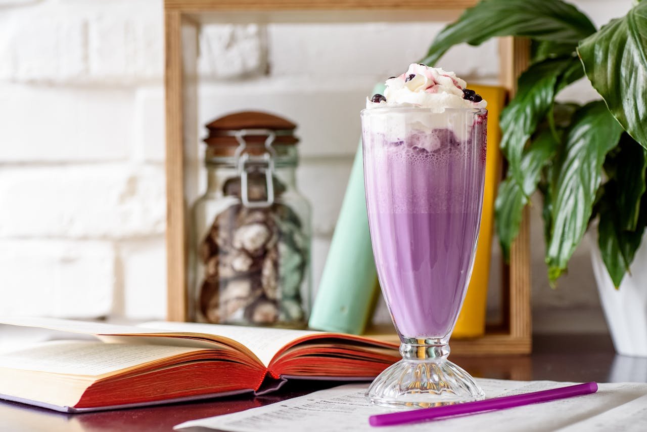 The Art of Drawing Readers In: Your attractive post title goes here A delicious purple milkshake topped with whipped cream next to open books and a plant.